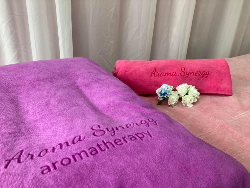 Treatment bed dressed in Aroma Synergy branded towels and fresh flowers in our Hong Kong studio